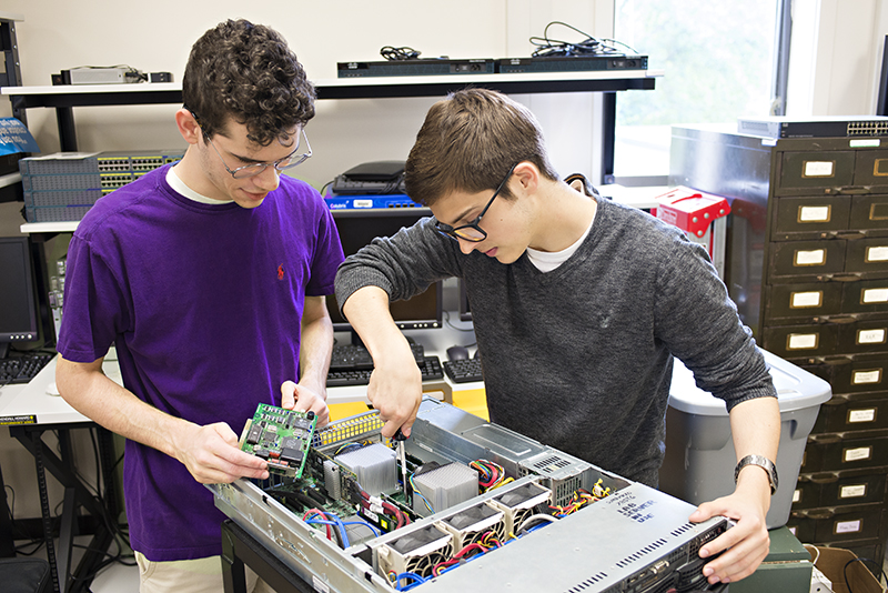 Photo of two students working on a computer tower
