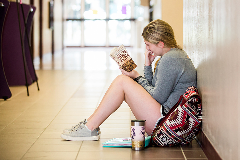 Photo of student in hall way reading book