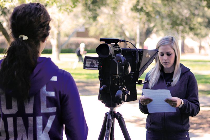 Photo of students reading script in front of video camera